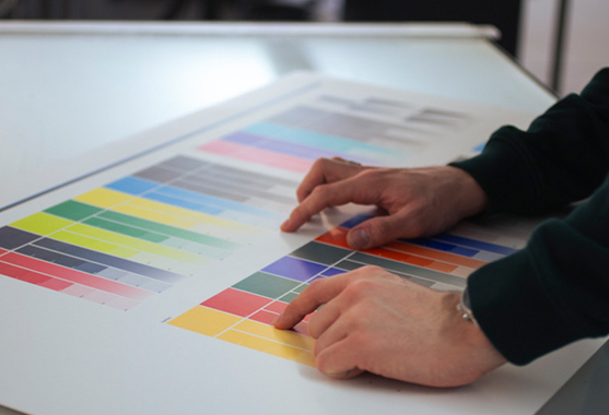 Un collaborateur vérifie les valeurs chromatiques et la qualité d'impression sur l'épreuve.