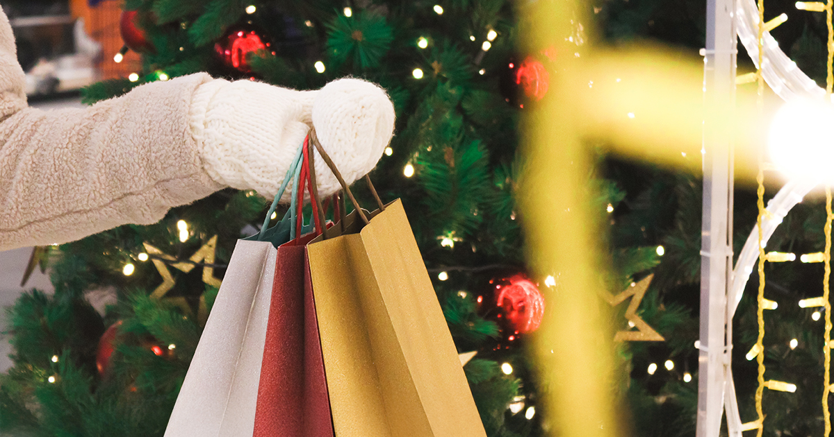 La main d'une personne tient des sacs de courses dans une ambiance festive.